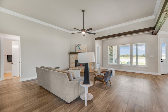 living room featuring light hardwood / wood-style floors, crown molding, a stone fireplace, and ceiling fan