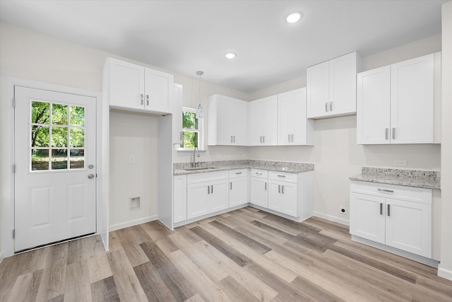 kitchen featuring light hardwood / wood-style floors, white cabinetry, light stone countertops, and a wealth of natural light