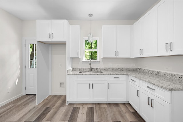 kitchen with decorative light fixtures, light hardwood / wood-style floors, sink, and white cabinetry