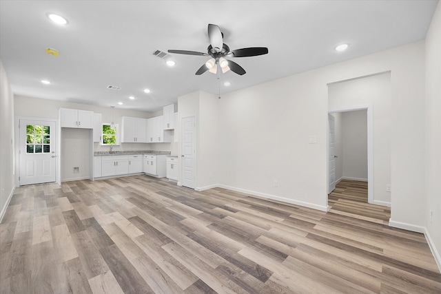 unfurnished living room with light wood-type flooring, sink, and ceiling fan