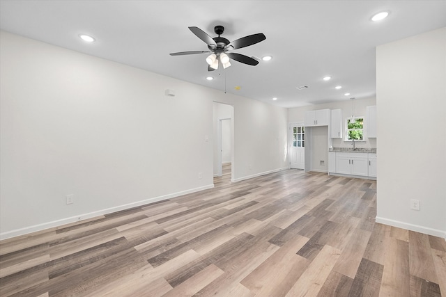 unfurnished living room with light hardwood / wood-style floors, ceiling fan, and sink