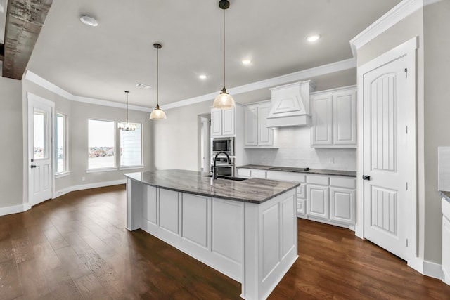 kitchen featuring premium range hood, stainless steel microwave, white cabinets, and sink