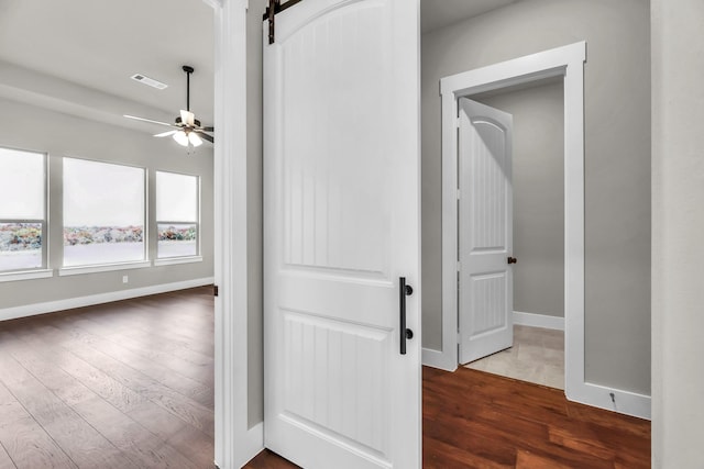 hallway with a barn door and dark hardwood / wood-style flooring