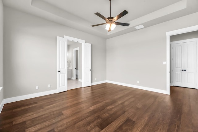 empty room featuring dark hardwood / wood-style flooring, a tray ceiling, and ceiling fan