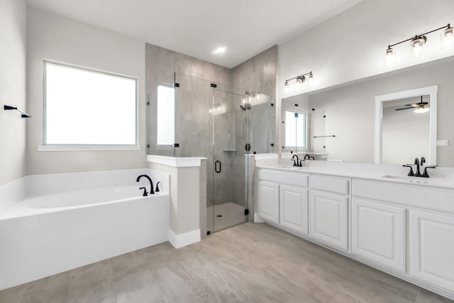 bathroom with ceiling fan, plenty of natural light, separate shower and tub, and vanity