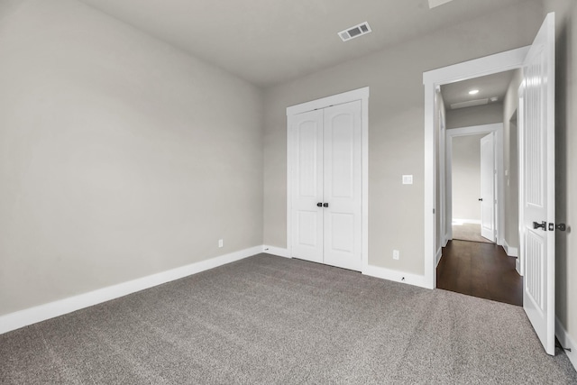 unfurnished bedroom featuring a closet and dark carpet