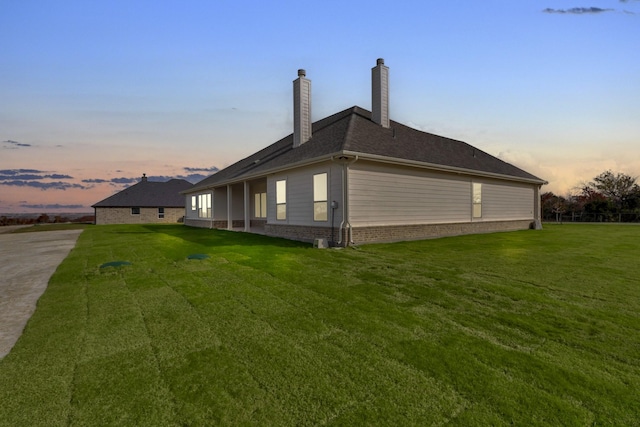 property exterior at dusk featuring a yard