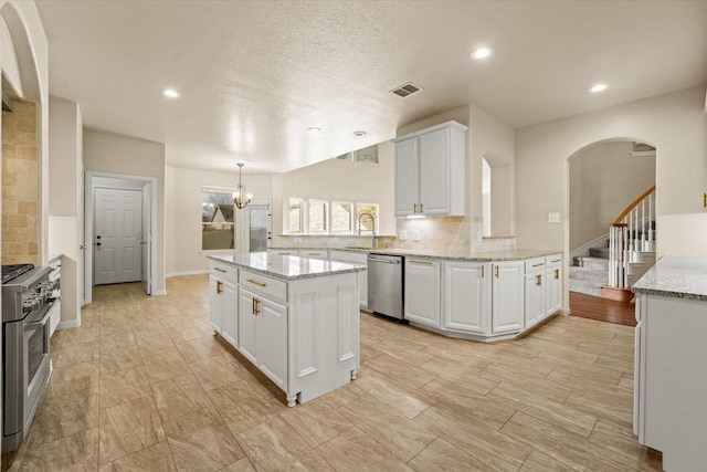 kitchen featuring white cabinets, sink, appliances with stainless steel finishes, a kitchen island, and kitchen peninsula