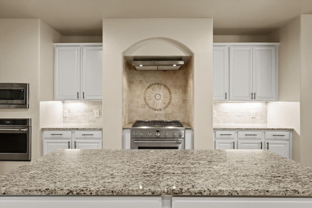 kitchen with decorative backsplash, stainless steel appliances, white cabinetry, and light stone counters