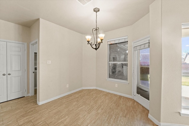 unfurnished dining area featuring light hardwood / wood-style flooring and an inviting chandelier