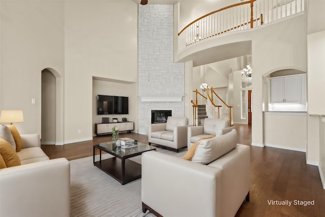 living room featuring a fireplace, a high ceiling, hardwood / wood-style flooring, and a notable chandelier