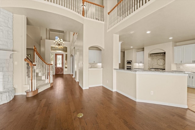 entrance foyer featuring hardwood / wood-style floors, a fireplace, a high ceiling, and an inviting chandelier