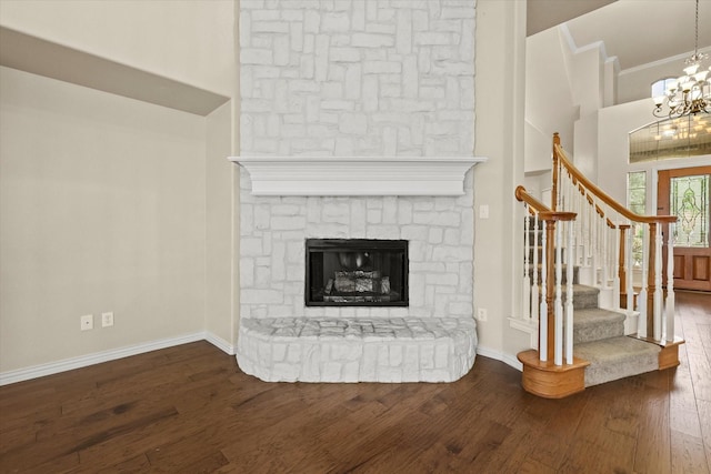 unfurnished living room with hardwood / wood-style flooring, a fireplace, a high ceiling, and a chandelier