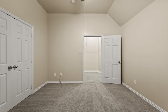 unfurnished bedroom with carpet flooring, a closet, and lofted ceiling