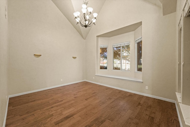 empty room with hardwood / wood-style floors, high vaulted ceiling, and an inviting chandelier