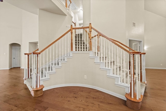 stairway featuring a towering ceiling and hardwood / wood-style flooring