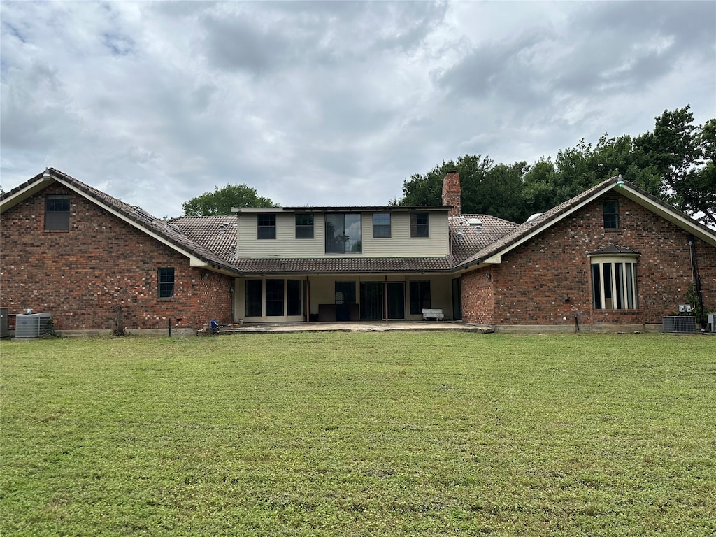 rear view of property with a patio area, a yard, and cooling unit