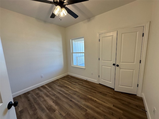 unfurnished bedroom with ceiling fan, dark wood-type flooring, and a closet