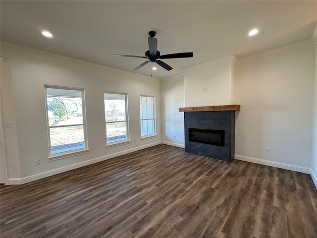 unfurnished living room featuring dark wood-type flooring, crown molding, a tiled fireplace, and ceiling fan