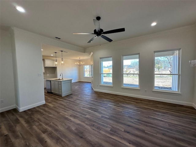 unfurnished living room featuring ceiling fan with notable chandelier, sink, dark hardwood / wood-style flooring, and crown molding