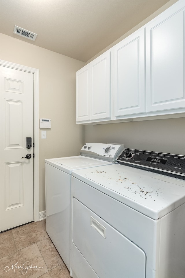 laundry room featuring washer and clothes dryer and cabinets