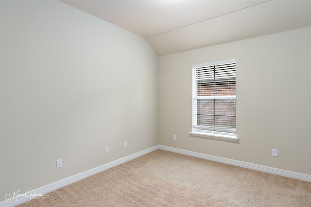 carpeted spare room with vaulted ceiling