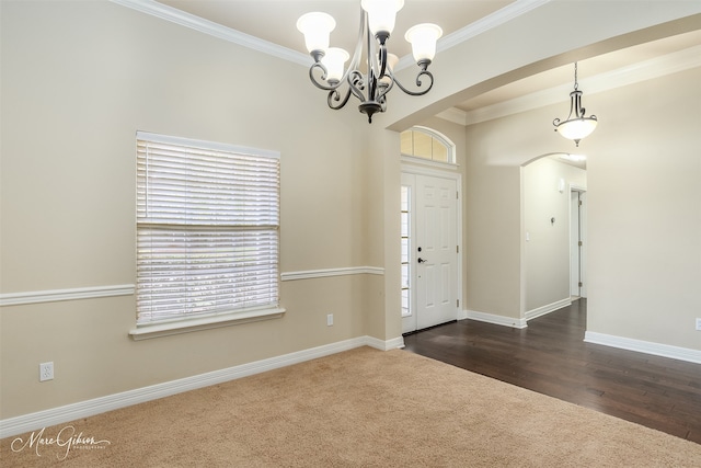 foyer entrance with dark hardwood / wood-style flooring, an inviting chandelier, and crown molding