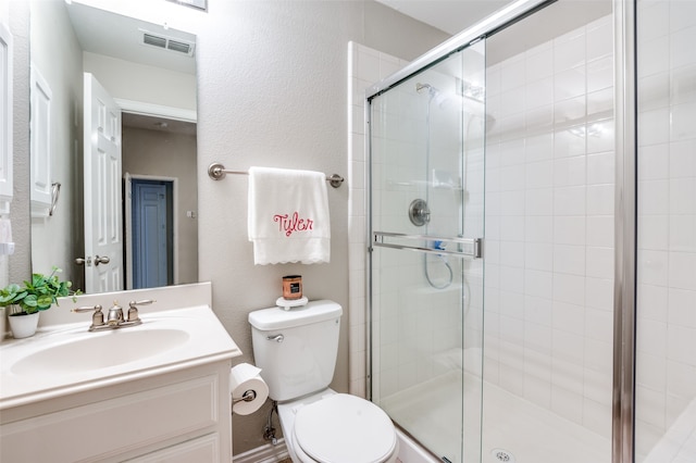 bathroom featuring a shower with shower door, vanity, and toilet