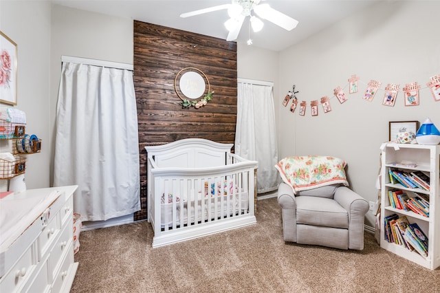 bedroom with ceiling fan, a nursery area, and carpet