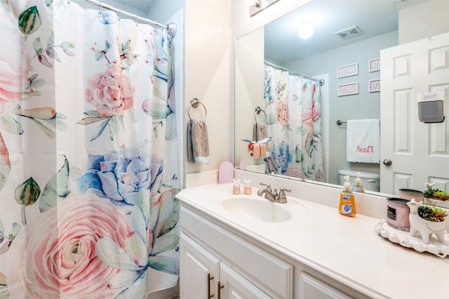 bathroom with curtained shower, vanity, and toilet