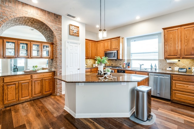 kitchen with stainless steel appliances, dark hardwood / wood-style floors, tasteful backsplash, and a center island