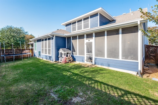 back of house with a trampoline, a yard, and a sunroom