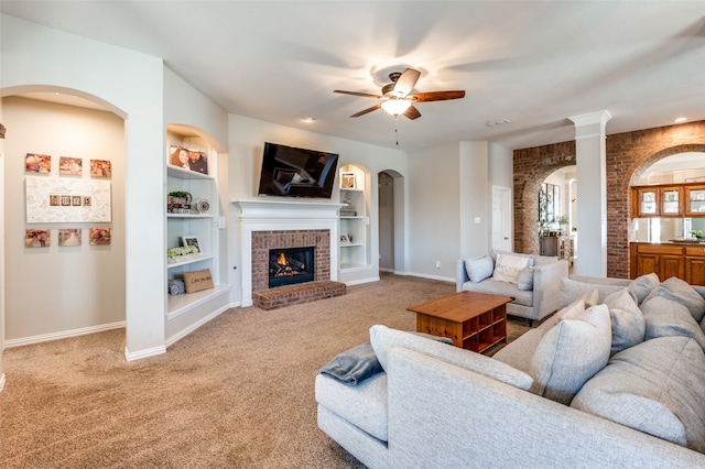 living room featuring a brick fireplace, ceiling fan, carpet flooring, and built in features