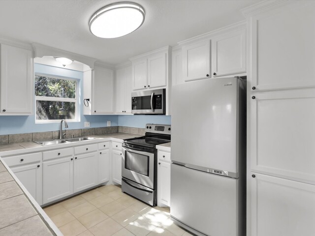 kitchen with tile countertops, white cabinets, sink, and appliances with stainless steel finishes