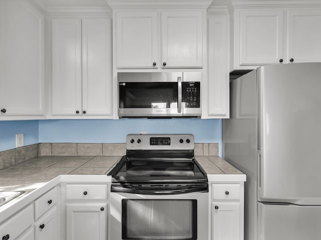 kitchen featuring white cabinetry, tile counters, and appliances with stainless steel finishes