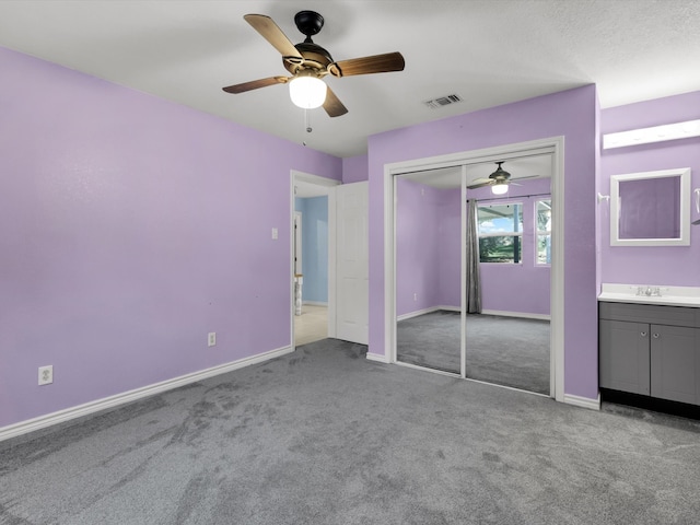 unfurnished bedroom featuring light carpet, a closet, ceiling fan, and sink