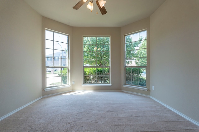 empty room with ceiling fan, light carpet, and a wealth of natural light