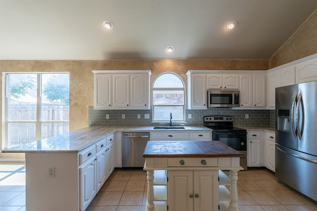 kitchen with a healthy amount of sunlight, lofted ceiling, a kitchen island, and stainless steel appliances