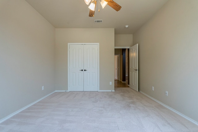 unfurnished bedroom featuring ceiling fan, light colored carpet, and a closet