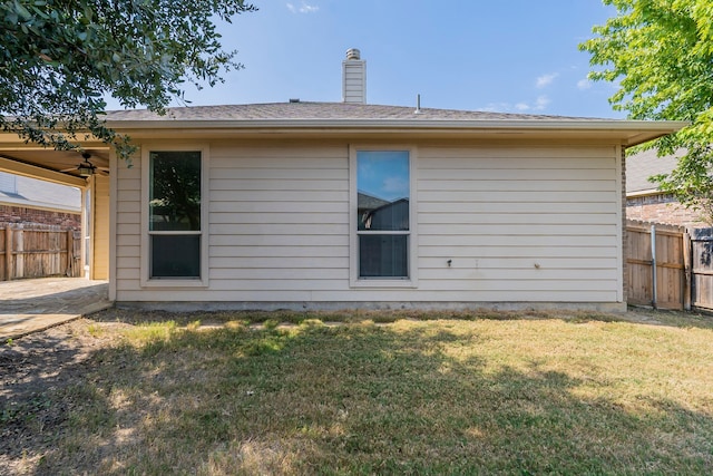 rear view of house with ceiling fan and a lawn