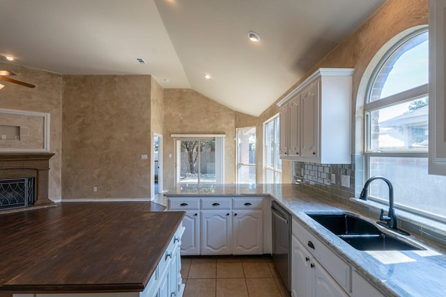 kitchen with lofted ceiling, white cabinetry, sink, and a wealth of natural light