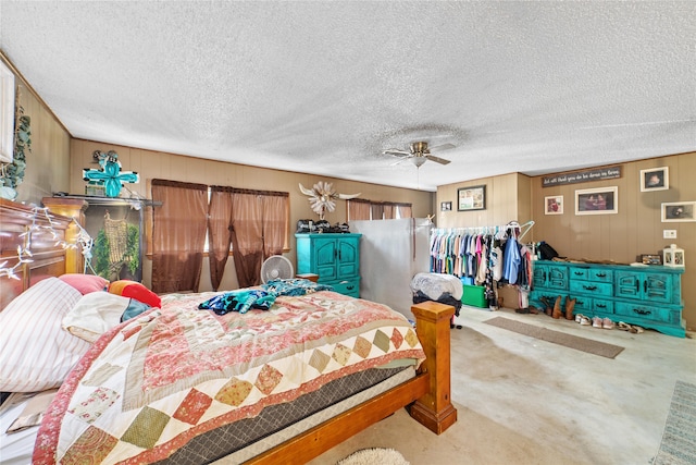 bedroom with wood walls, ceiling fan, light carpet, and a textured ceiling