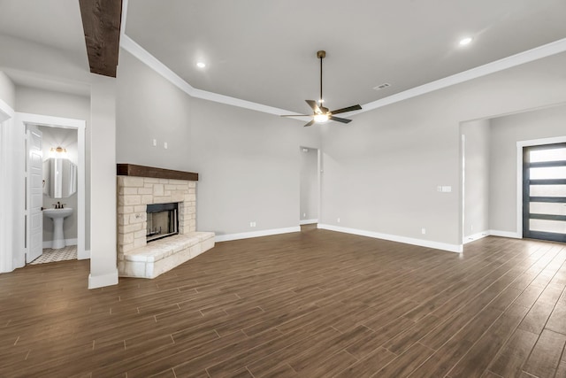 unfurnished living room featuring a fireplace, crown molding, ceiling fan, and dark wood-type flooring