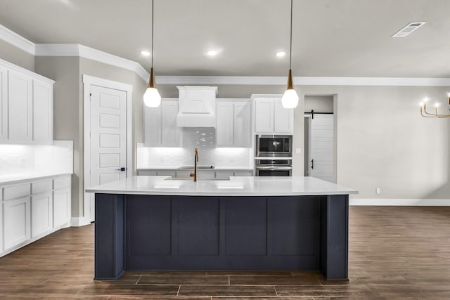 kitchen featuring tasteful backsplash, a barn door, decorative light fixtures, and appliances with stainless steel finishes