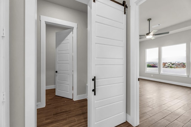 hall with a barn door and dark hardwood / wood-style flooring