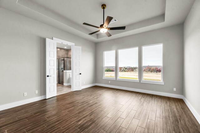 unfurnished room featuring dark hardwood / wood-style flooring, a raised ceiling, a wealth of natural light, and ceiling fan