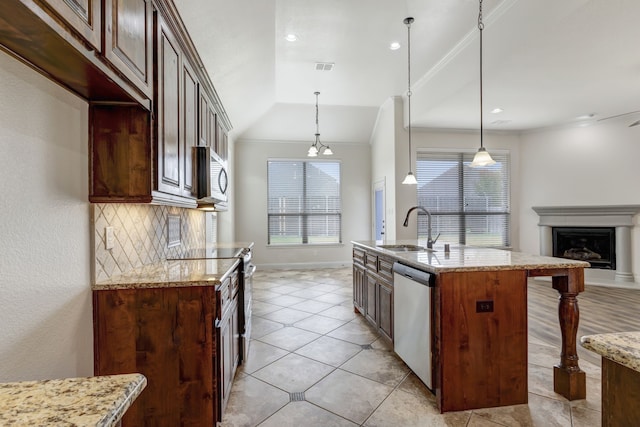 kitchen featuring a kitchen island with sink, light stone countertops, stainless steel appliances, and sink