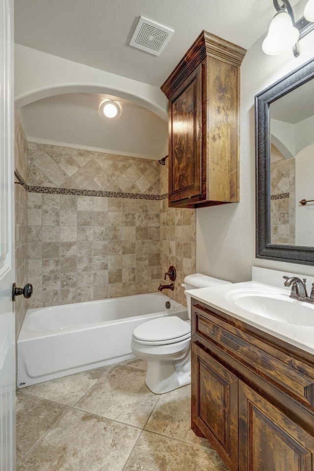 full bathroom featuring tiled shower / bath combo, vanity, toilet, and a textured ceiling