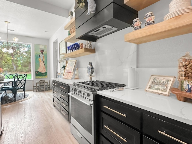 kitchen featuring pendant lighting, gas stove, light hardwood / wood-style floors, an inviting chandelier, and light stone countertops