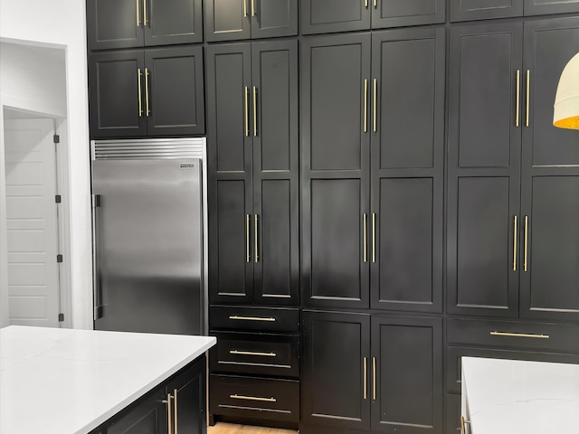 kitchen featuring light stone counters and built in refrigerator